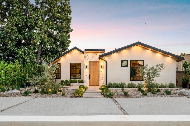 Modern single story house with a minimalist garden at sunset featuring clean lines and warm lighting